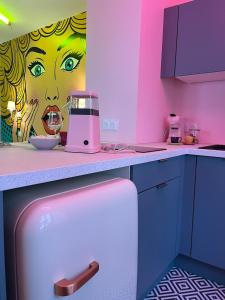 a kitchen with a pink refrigerator and a painting of a woman at Atyp'Home POP avec Balnéo en centre-ville in Bourg-en-Bresse +10 photos