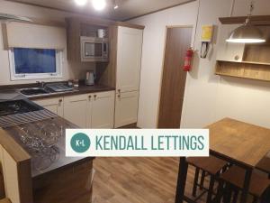 a kitchen with a table and a kitchen with a sign that reads k rental settings at Elan in Selsey
