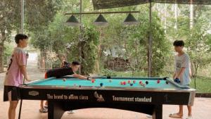 three children playing with a pool table in a park at Maison De Mai Hich in Mai Châu
