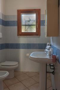 ein Badezimmer mit Waschbecken und Toilette und einem Fenster in der Unterkunft Charming Le Dimore di Budoni 1 Bed Apt B4 sleeps 4 in Budoni
