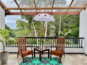 Swastha Ayurveda Villa في هيكادوا: فناء مع كرسيين وطاولة ومظلة