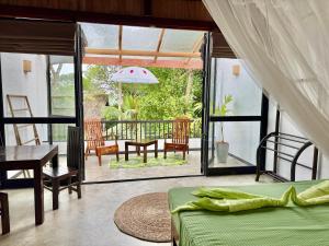 a bedroom with a bed and a table and a patio at Swastha Ayurveda Villa in Hikkaduwa