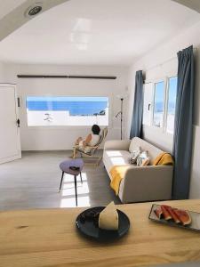 a living room with a bed and a person sitting in a chair at Casa Lila, paz junto al mar in Guatiza