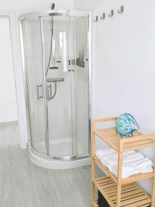 a bathroom with a shower and a shelf with towels at Casa Lila, paz junto al mar in Guatiza