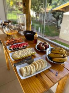 a wooden table topped with plates of food and fruit at Hospedaria Paiol in São Bento do Sapucaí