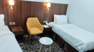 a room with two beds and a chair and a desk at فندق مواسم العزيزية in Al ‘Azīzīyah