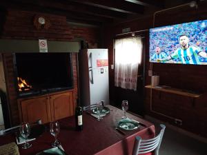 comedor con mesa con copas de vino y TV en Brisas del Sur, en El Bolsón