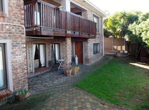 a brick house with a balcony and a yard at Macaw Villa in Mossel Bay