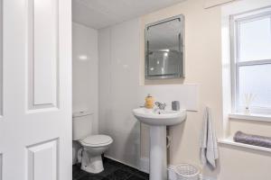 a white bathroom with a toilet and a sink at Keith - Spacious 4 bed house in Keith