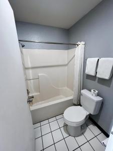 ein Badezimmer mit einem weißen WC und einer Badewanne in der Unterkunft Budget Inn Motel in San Antonio