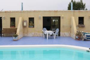 Un patio con mesa y sillas junto a una piscina. en Maravilla Bungalows, en Cotillo