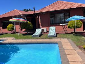 two chairs and umbrellas in front of a house at MAU Family ROOM in Krugersdorp