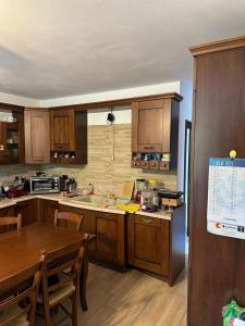 a kitchen with wooden cabinets and a table and a sink at B & B Lmc LA MADONNINA CHALET in Casteggio