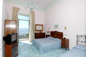a bedroom with a bed and a tv and a balcony at Hotel Fontana in Amalfi