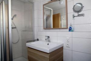 a white bathroom with a sink and a mirror at Achterhook in Norden +20 photos