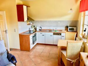 a kitchen with white cabinets and a table with a microwave at Straminke 4b Wohnung Dünentraum in Groß Kirr