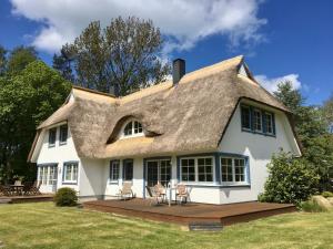 a white house with a thatched roof and chairs at Straminke 4b Wohnung Dünentraum in Groß Kirr
