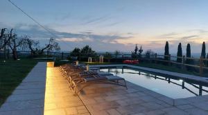 a swimming pool with a row of chairs next to it at Villa Sunbathing in Montelupo Fiorentino