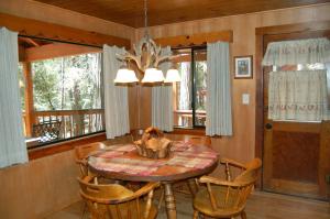 a dining room with a table and chairs and windows at Deer Den in Wawona