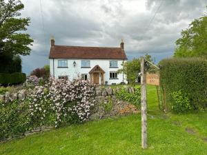 a white house with a stone fence and flowers at Little Howle Farm Barn in Ross on Wye