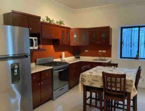 cocina con armarios de madera, mesa y nevera en Quinta Maderoo 5, en Parras de la Fuente