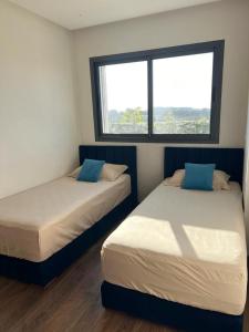 カサブランカにあるLuxury 2 bedroom flat in Tamaris Dar Bouazzaの窓のある部屋にベッドが2つある +4枚の写真