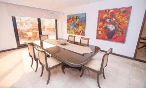 a dining room with a table and chairs and paintings at Hotel Dann Carlton Cali in Cali