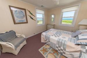 a bedroom with two beds and a chair and windows at A Shore Thing in Southern Shores +81 photos