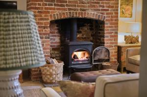 un soggiorno con camino in mattoni e stufa di Grints Cottage a Burnham Thorpe