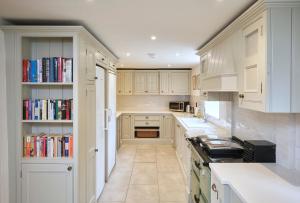 una cucina con armadi bianchi e librerie di Grints Cottage a Burnham Thorpe