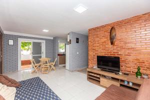a living room with a brick wall and a flat screen tv at Memora Guesthouse Pontal do Paraná - Casa inteira ou Quartos a duas quadras da praia e próxima a Ilha do Mel in Pontal do Paraná