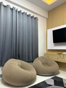 ein Wohnzimmer mit zwei Ottomanen und einem Fernseher in der Unterkunft THE24 Residence in Yala