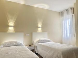 1 Schlafzimmer mit 2 Betten und 2 Leuchten an der Decke in der Unterkunft Hostal La Sierra Cabárceno in Sarón