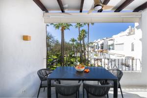 a blue table and chairs on a balcony with palm trees at Apartamentos Urb, La Alcazaba 614 y 642 Banus Marbella in Marbella