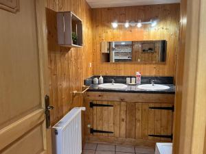 Baño con 2 lavabos en una pared de madera en ferme des grands blaise, en La Bresse