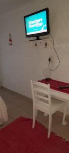 a television on a wall with a table and a chair at Macaw Villa in Mossel Bay