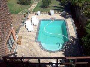 an overhead view of a swimming pool with two white chairs at Macaw Villa in Mossel Bay
