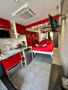 - une cuisine avec des placards rouges et un lit rouge dans une chambre dans l'établissement AphrodiX Village naturiste, au Cap d'Agde