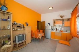 a kitchen with orange cabinets and a tv in it at Apartments Meri - 1 in Lopar