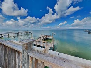 a wooden dock on the water with clouds in the sky at Frisco- Flats in Rockport
