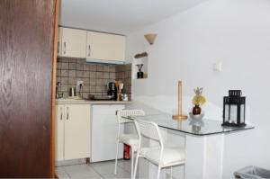 a kitchen with white cabinets and a table and chairs at Ζoe Studios in Kythira