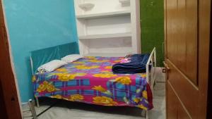 a small bedroom with a bed with a colorful blanket at Kumbh Home Stay in Jhūsi