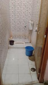 a bathroom with a tiled floor with a blue bucket at Kumbh Home Stay in Jhūsi