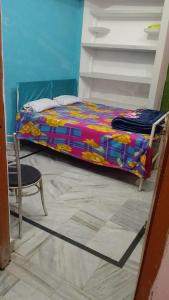 a small bed in a room with a chair at Kumbh Home Stay in Jhūsi
