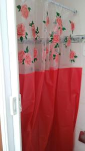 a red shower curtain with pink roses on the wall at Apartamento Casa da Praia in Cabo Frio