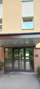 une entrée d'un bâtiment avec une grande porte vitrée dans l'établissement Cichy i przyjemny pokój na Muranowie, à Varsovie