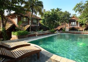 a swimming pool with a bench in front of a house at Punnamada Resort in Alleppey