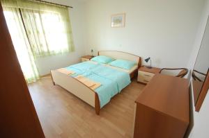 a bedroom with a bed with blue sheets and a table at Apartment Djuka in Njivice