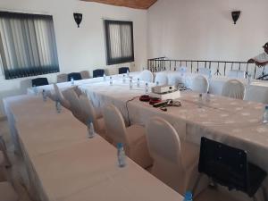 una habitación con una mesa larga con mesas y sillas blancas en Sen hôtel, en Sali Nianiaral 46 fotos más