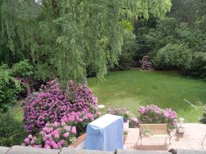 einen Garten mit rosa Blumen, einem Tisch und einer Bank in der Unterkunft Villa Kükenkamp in Rätzlingen